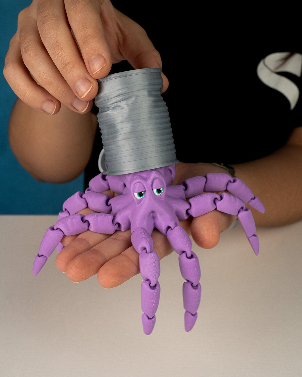 Gus the Octopus is a purple articulated 3D printed toy emerging from a can and resting in a hand by 3DPRINTSWA from the Articulated Animals collections