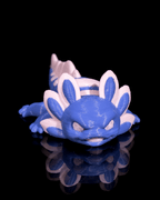 Blue and white 3D-printed dragon-like creature on a black reflective surface