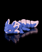 Blue and pink toy lizard on a black reflective surface
