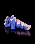 Blue and pink toy dragon on a black reflective surface