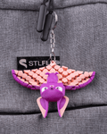 Bat Keychain in purple and pink with articulated wings and hanging rings displayed on gray fabric by 3DPRINTSWA