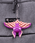 Bat Keychain in purple and pink with articulated wings and hanging rings displayed on gray fabric by 3DPRINTSWA