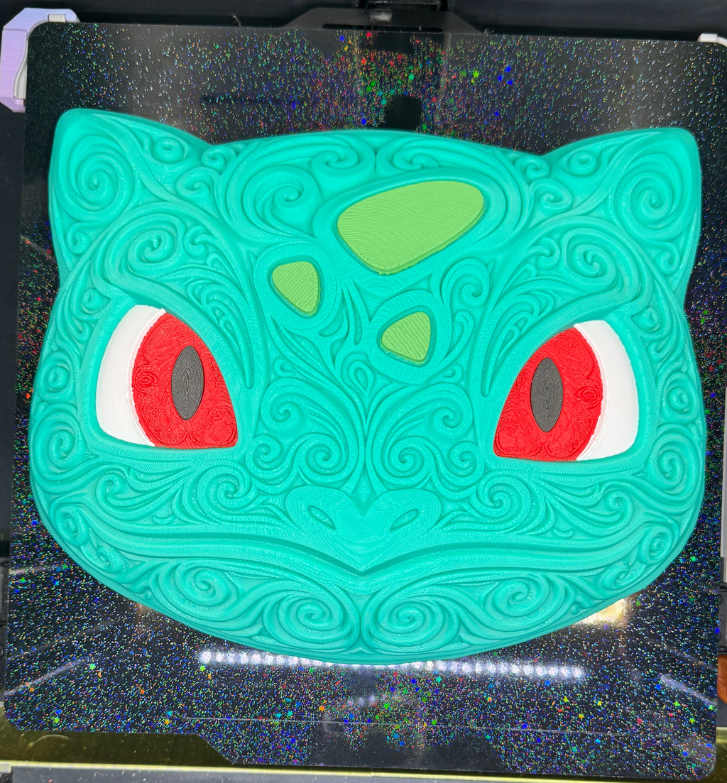 Overhead front view of Bulbasaur wall decor on a textured printer plate, showing the complete filigree design.
