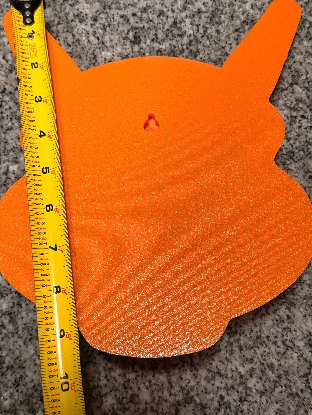 Rear view of Charizard wall art beside a vertical tape measure, showing the flat back and keyhole slot.