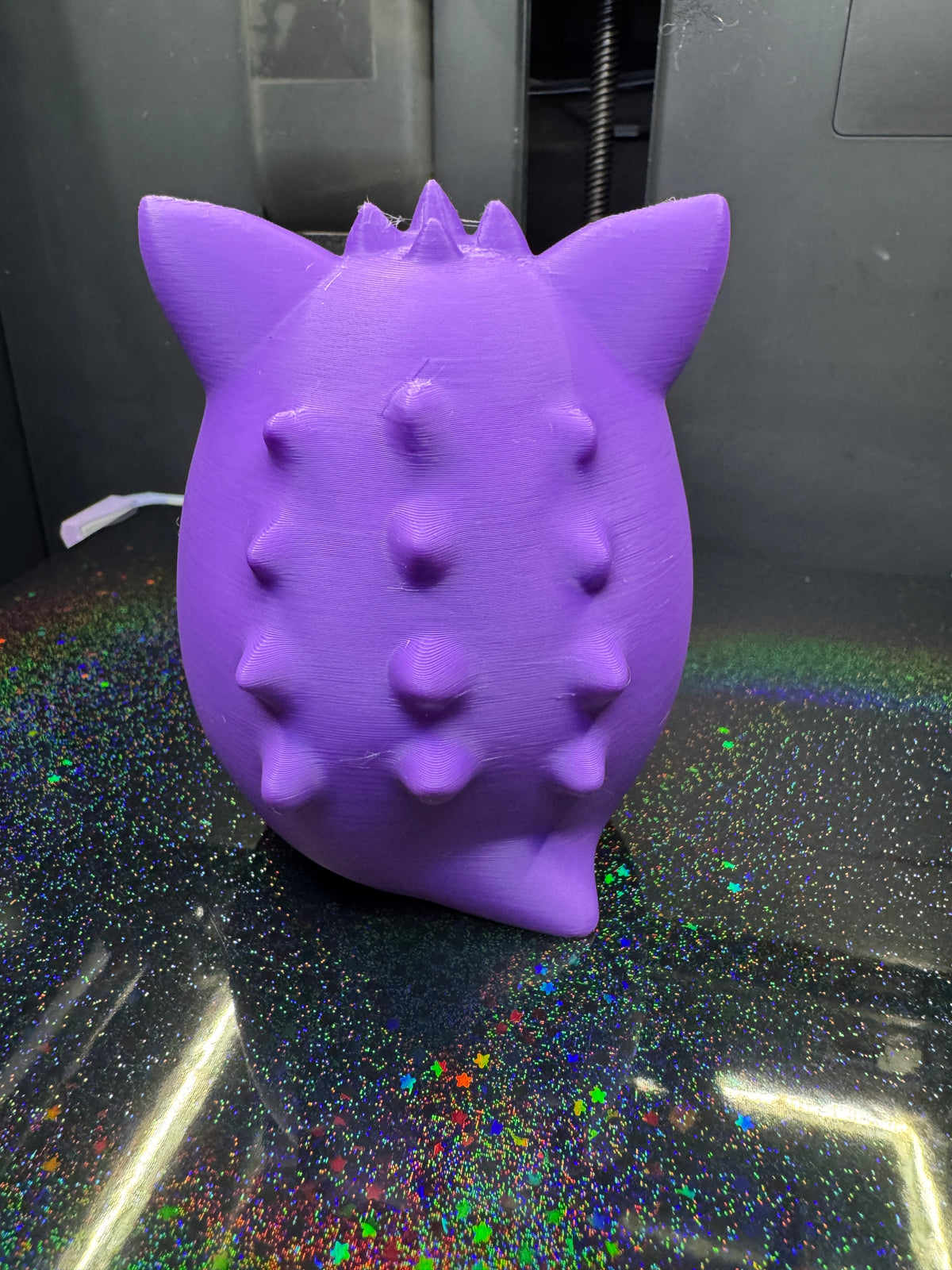 Rear view of the purple Derpy Gengar figure showing pointed ears, rows of back spikes, and a small tail.