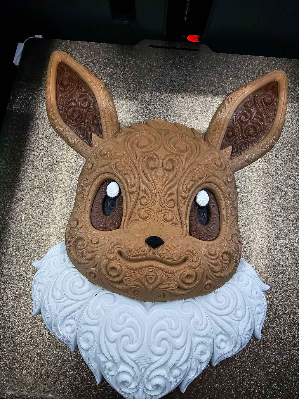 Front view of Eevee wall art on a printer plate showing ornate raised scrollwork and multicolor details.