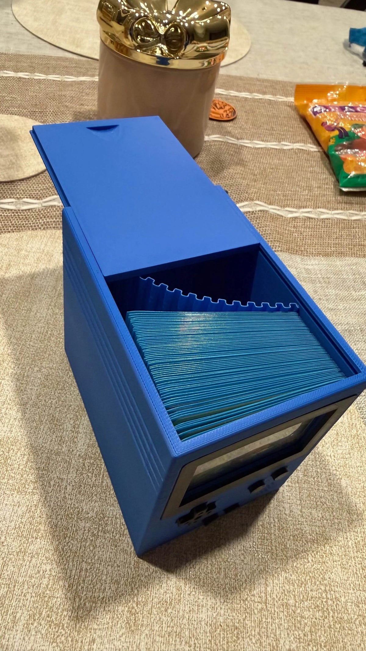 Blue deck box open with sleeved cards inside.