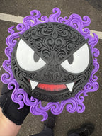 Gastly wall art held outdoors, showing its raised black filigree and purple ghostly border.