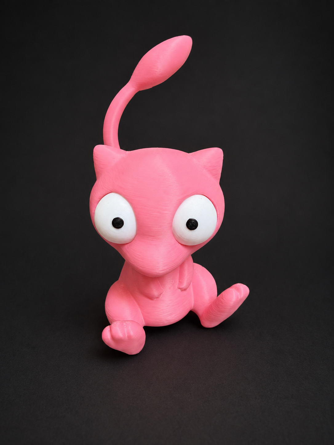 Angled front view of pink Goofy-Eyed Mew sitting with its feet forward and tail raised.