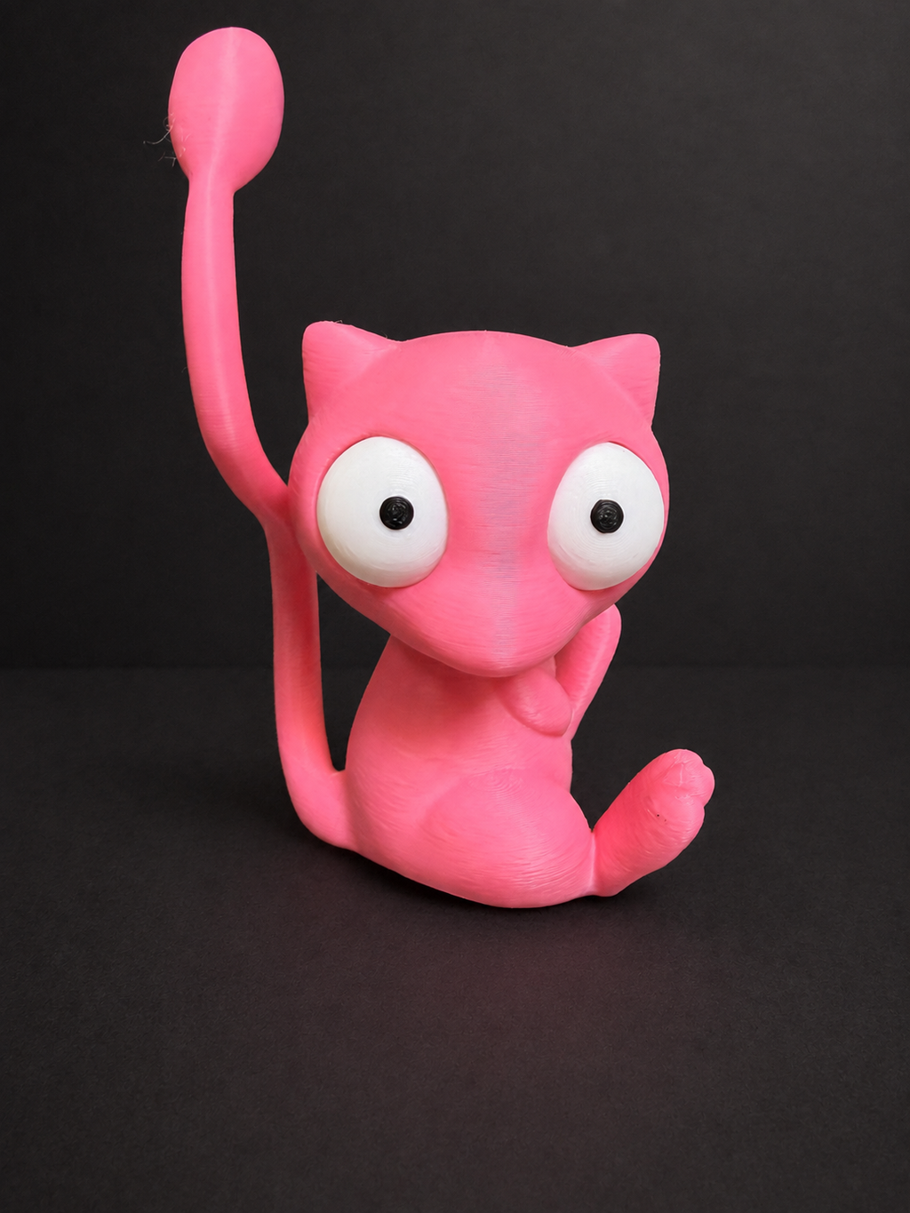 Three-quarter view of pink Goofy-Eyed Mew with white articulated eyes and its tail curling upward beside its head.