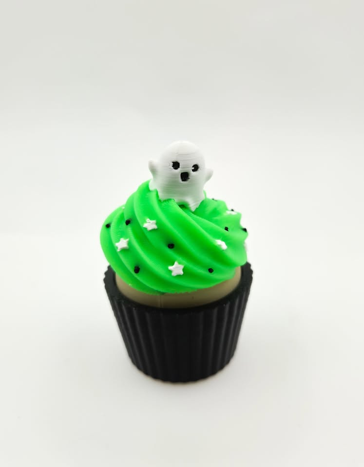 Green decorative cupcake with white ghost topper and black wrapper.