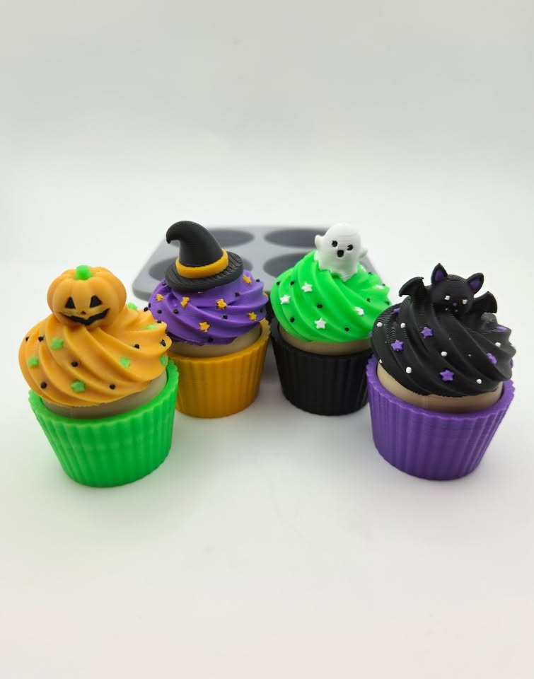 Four Halloween cupcake figures with pumpkin, witch, ghost and bat toppers displayed beside their tray.
