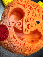 Close view of Halloween Pikachu's orange filigree face showing hollow eyes and mouth, black nose, and a red cheek.