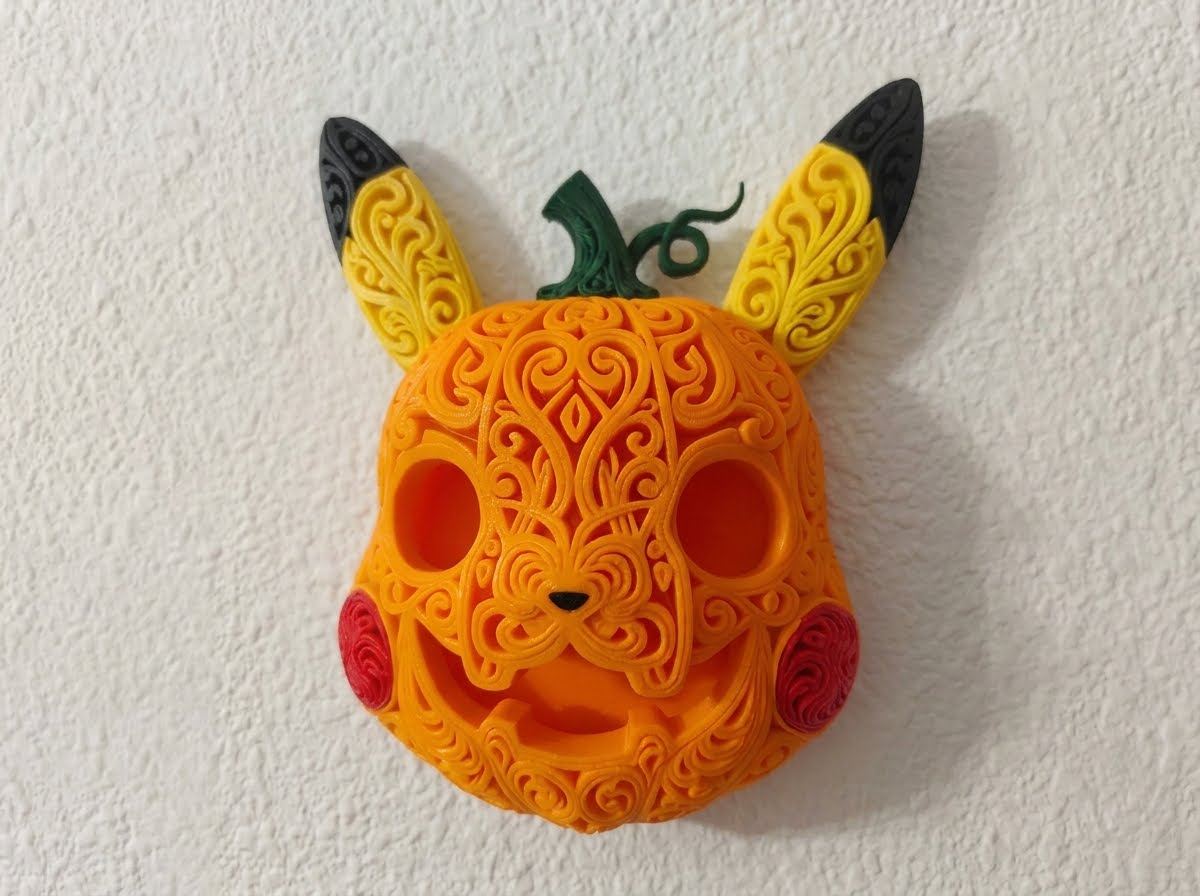 Halloween Pikachu pumpkin wall art mounted on a white wall, with orange filigree, yellow and black ears, red cheeks, and a green stem.