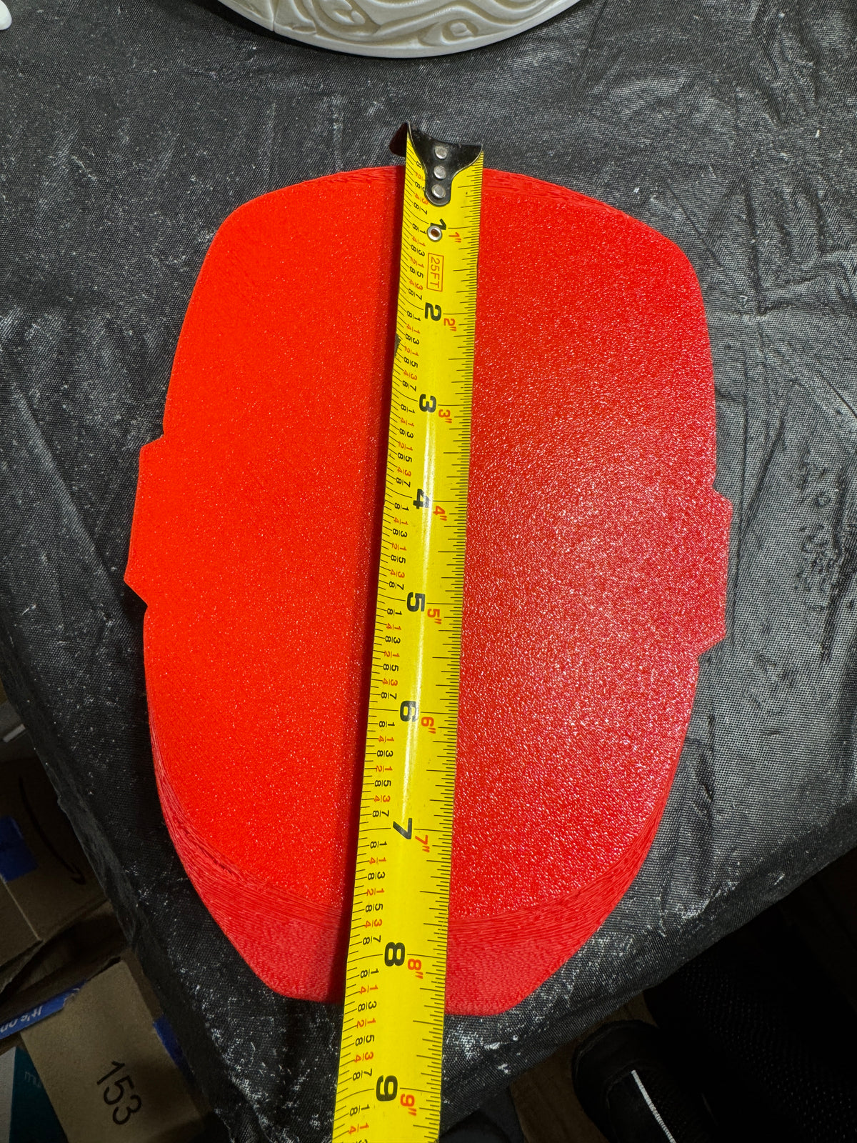 Flat red back of the Iron Man wall piece beside a tape measure showing its approximate height.