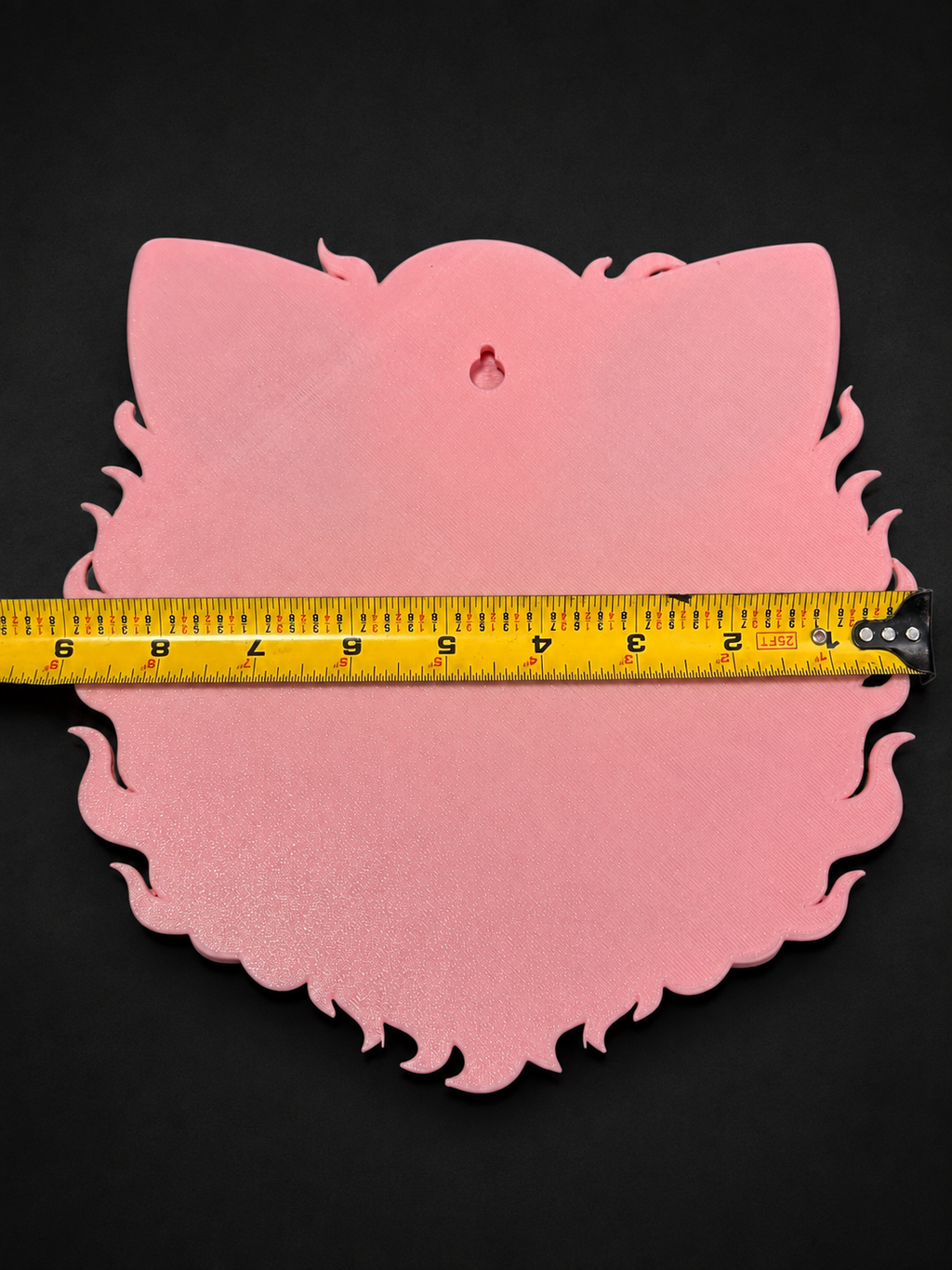 Pink back of Jigglypuff wall art showing a keyhole hanging slot and tape measure across its width.