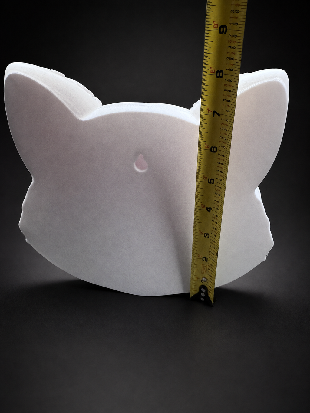 Back of Korin cat wall art beside a vertical tape measure showing its approximate height and keyhole slot.
