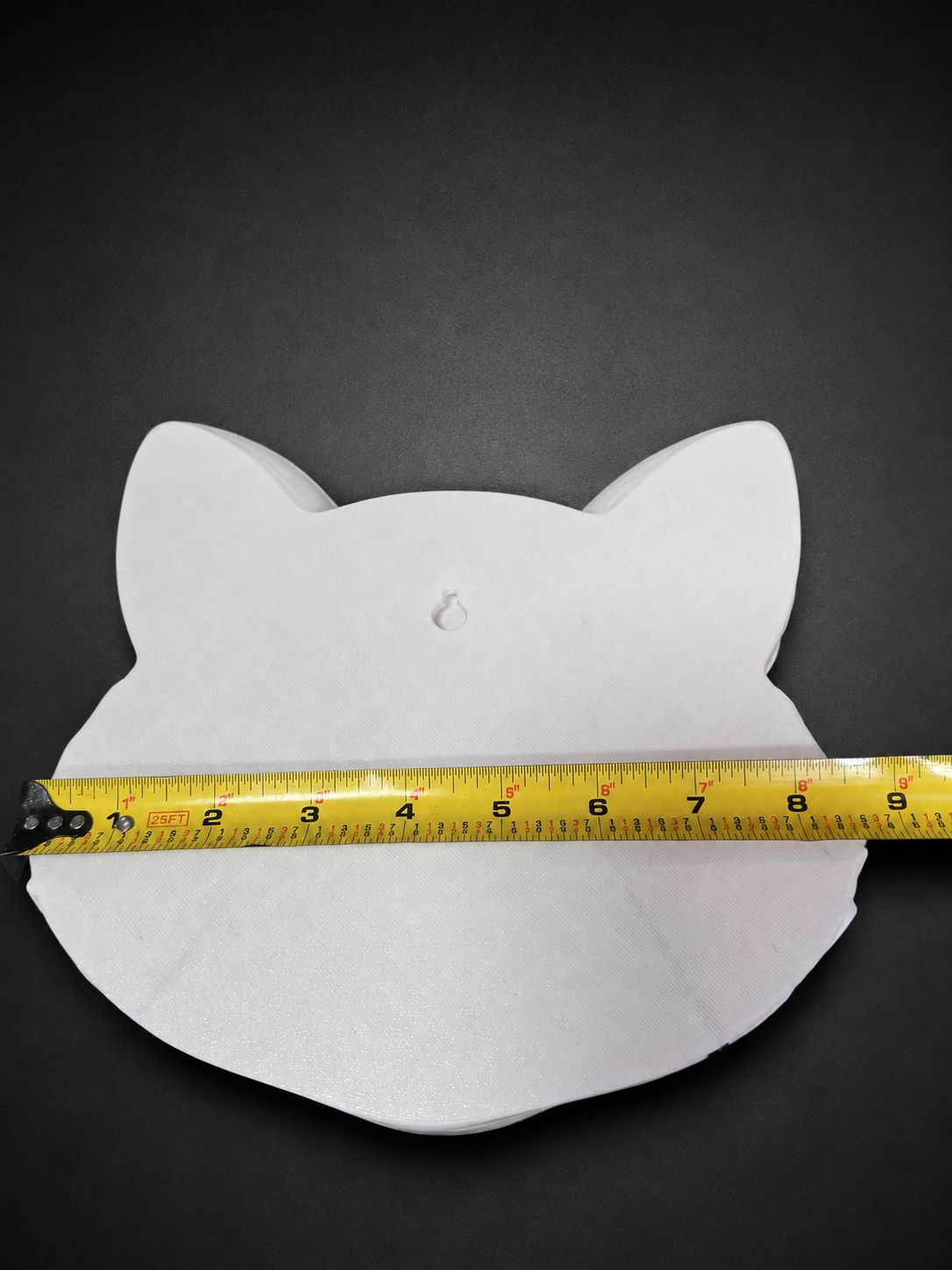Flat white back of Korin wall art with a keyhole hanging slot and a tape measure across its width.