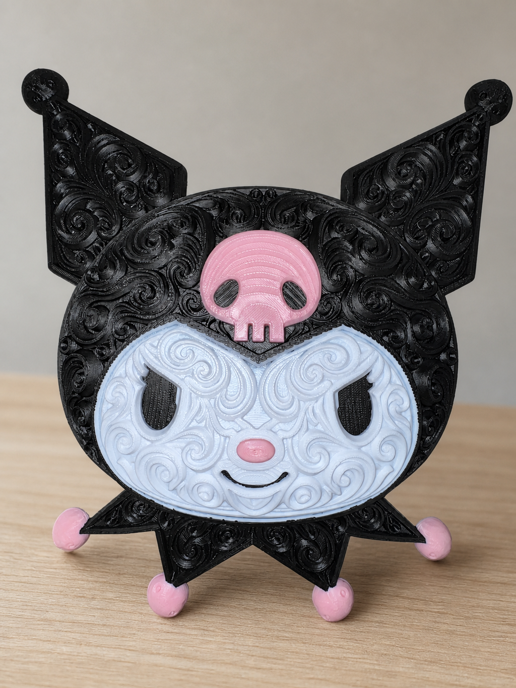 Front of black, white, and pink Kuromi wall art with raised filigree, a pink skull, and pink accents on a wood tabletop.