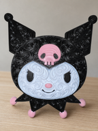 Front of black, white, and pink Kuromi wall art with raised filigree, a pink skull, and pink accents on a wood tabletop.