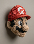 Angled view of Mario wall art with a red M cap, tan raised filigree face, and black mustache mounted on a light wall.