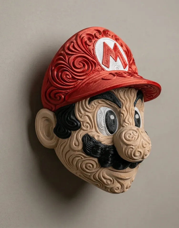 Angled view of Mario wall art with a red M cap, tan raised filigree face, and black mustache mounted on a light wall.