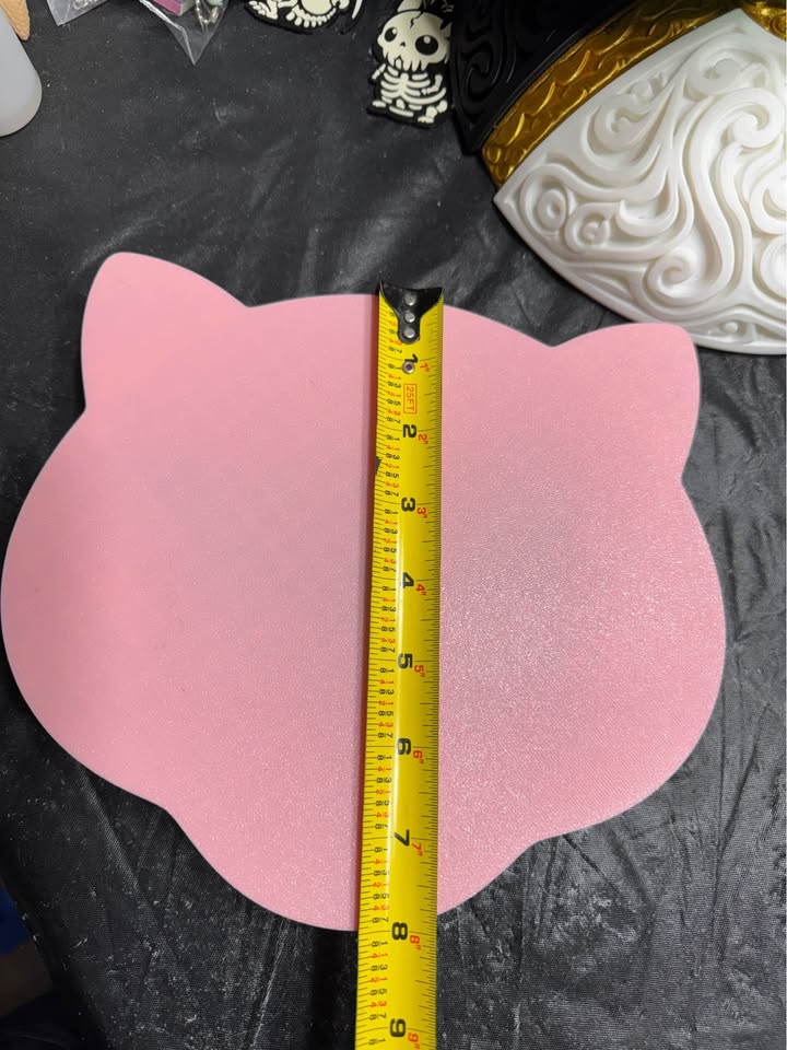 Flat pink back of Mew wall art with a vertical tape measure showing its approximate height.