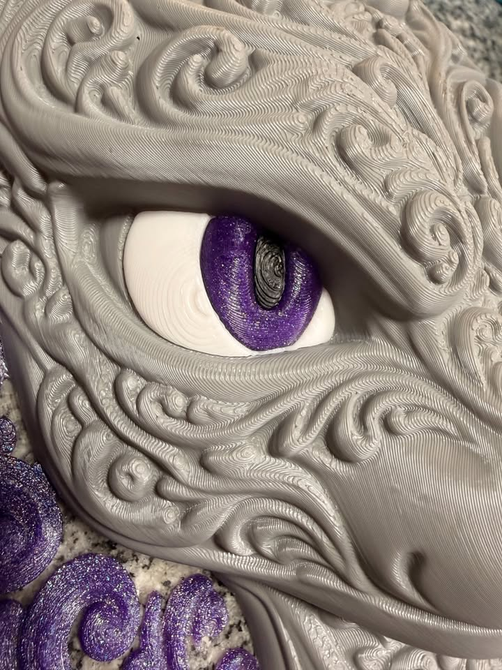 Close-up of Mewtwo wall art showing a purple glitter eye, white eye surround, and raised gray filigree texture.
