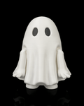Front view of a white Mood Ghost desk toy with black eyes, lowered arms, and feet visible against a black background.