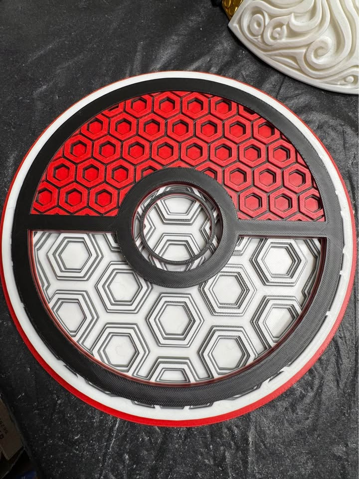 Round red, white, and black Mosaic Poké Ball wall plaque with raised hexagonal patterns and a central circular button.
