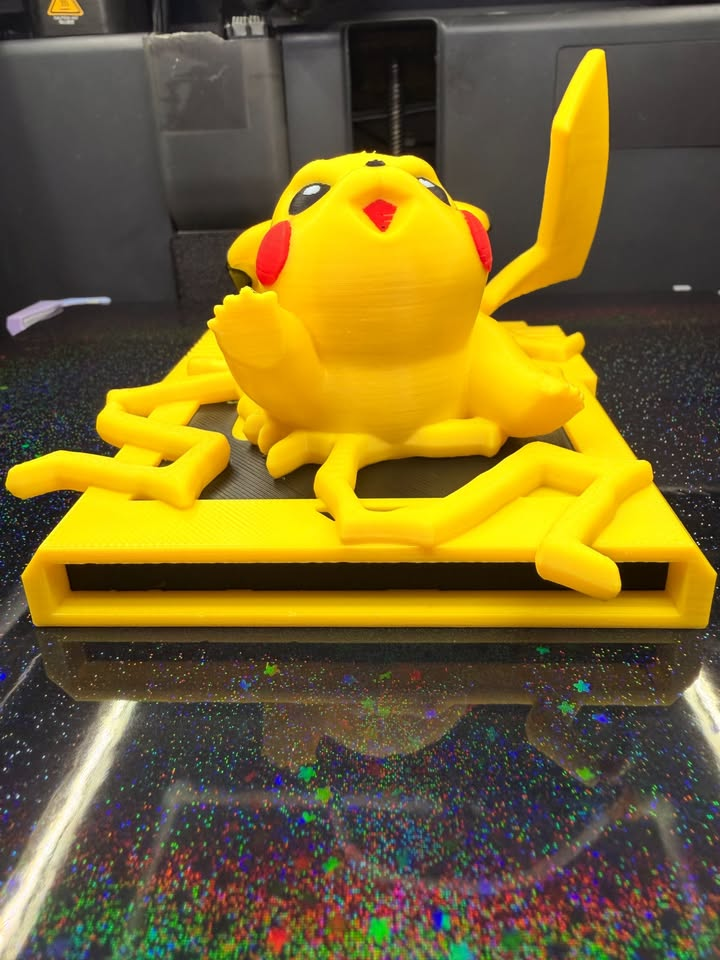 Low front view of Pikachu Game Boy wall art showing red cheeks, a raised paw, lightning details, and the dimensional base.