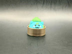 Turquoise Bulbasaur dumpling clicker with a green bulb and spots in a brown steamer-style base.