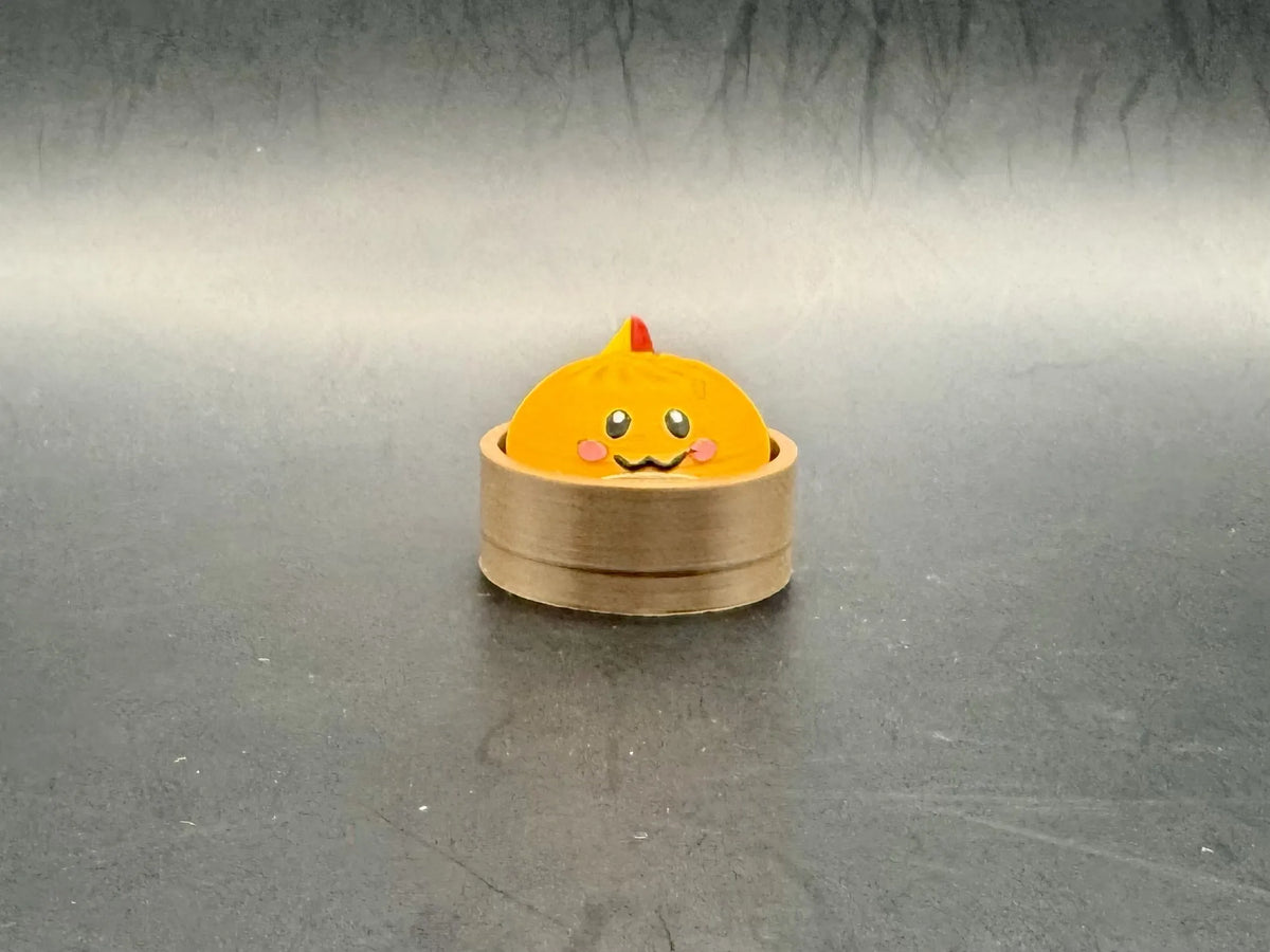 Orange Charmander dumpling clicker with a small tail and pink cheeks in a brown steamer-style base.