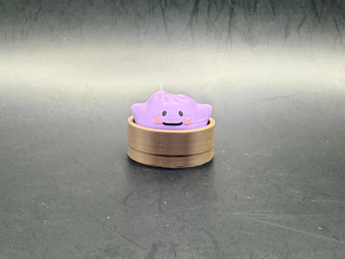 Purple Ditto dumpling clicker with a simple smiling face in a brown steamer-style base.