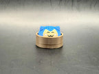 Blue Snorlax dumpling clicker with a cream face and closed eyes in a brown steamer-style base.