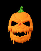 Close front view of the pumpkin mask showing scowling eye openings and dripping carved-pumpkin details.
