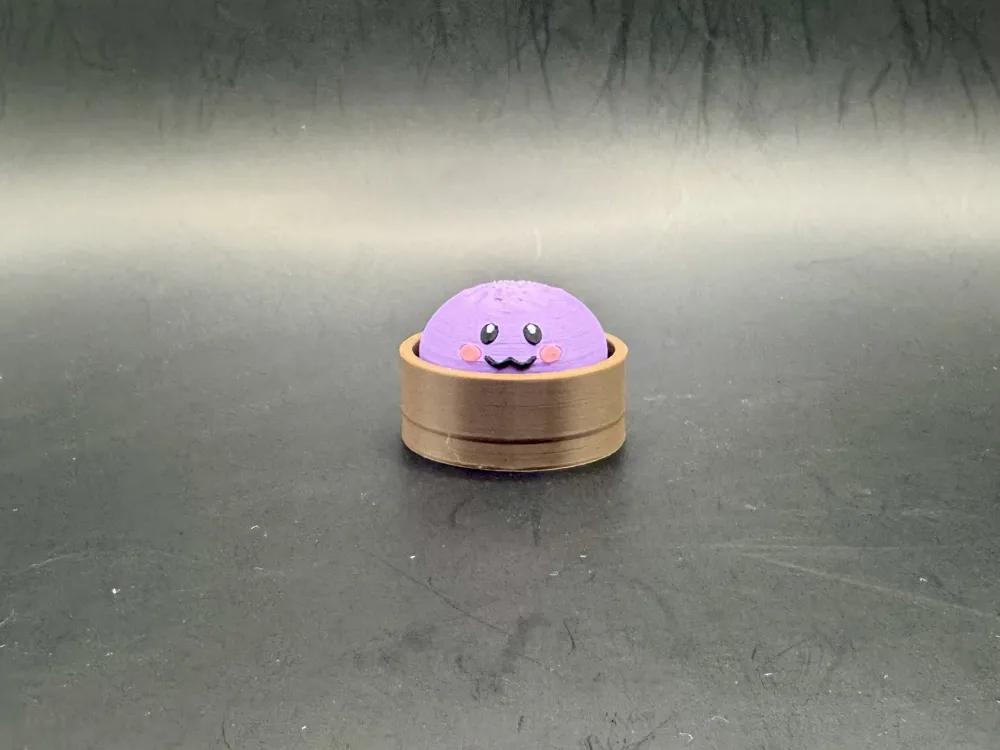 Regular purple dumpling clicker with a smiling face and pink cheeks in a brown steamer-style base.