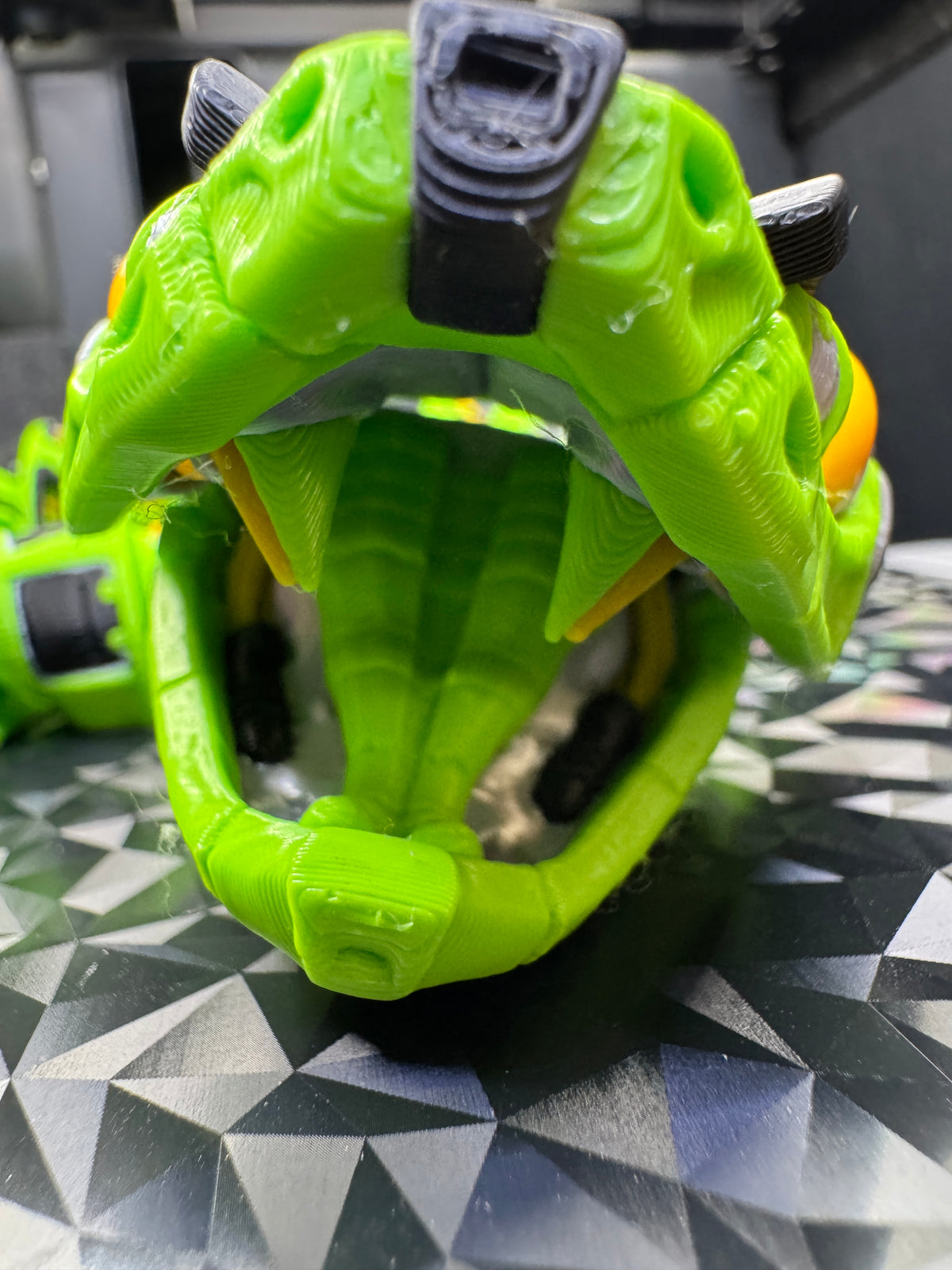 Close front view of the lime green robotic rattlesnake with its mouth open, showing fangs and tongue.