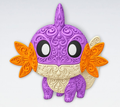 Front view of Shiny Mudkip Pokémon filigree wall art in purple, cream, orange, black and white with raised decorative scrollwork.