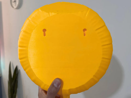 Back of the yellow smiley balloon wall decor showing two built-in keyhole mounting slots.