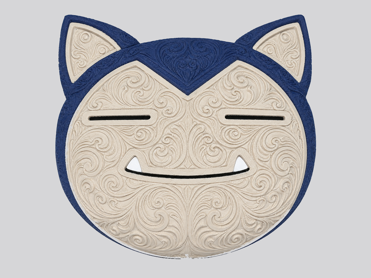 Front detail of cream and dark blue Snorlax wall art showing raised ornate scrollwork, closed eyes, and a smiling mouth.