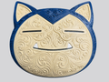 Snorlax wall art with a cream filigree face, dark blue border and ears, closed black eyes, and two white teeth on a plain gray background.