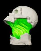 White Toxic Skull Lamp with an open jaw and bright green flowing center, shown from the side left view against black.