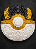 Black, gold, and white Ultra Ball wall art with raised ornate filigree and a white central button on a dark background.