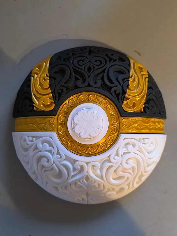 Ultra Ball filigree wall art mounted on a light wall, showing black and gold upper panels and a white lower half.