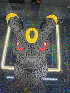 Front view of black Umbreon filigree wall art with yellow rings and red eyes resting on a patterned printer plate.